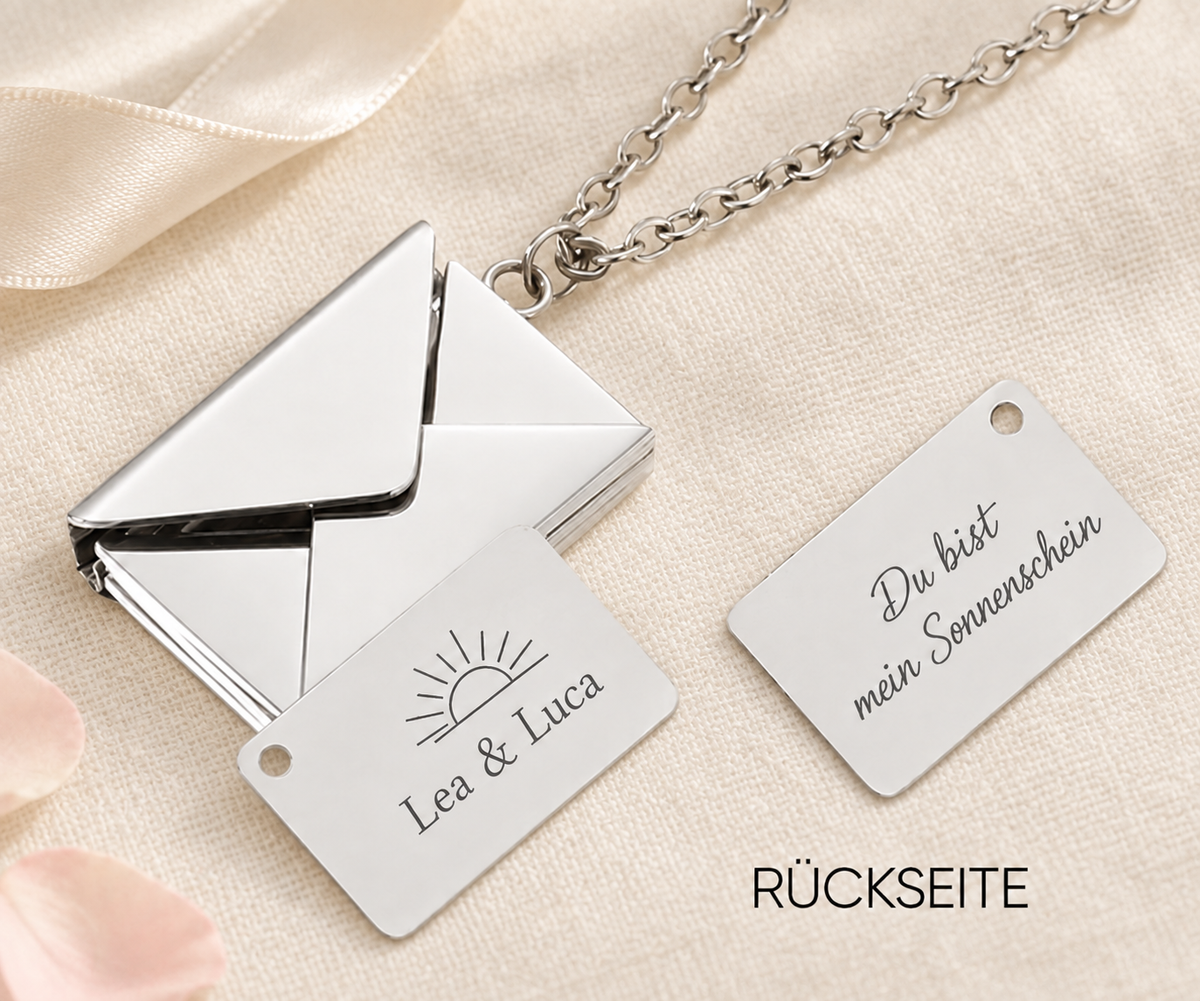 Silberfarbene Liebesbrief-Kette mit geöffnetem Umschlag und Gravur Lea & Luca mit Sonne auf hellem Leinen; daneben die Rückseite Du bist mein Sonnenschein.